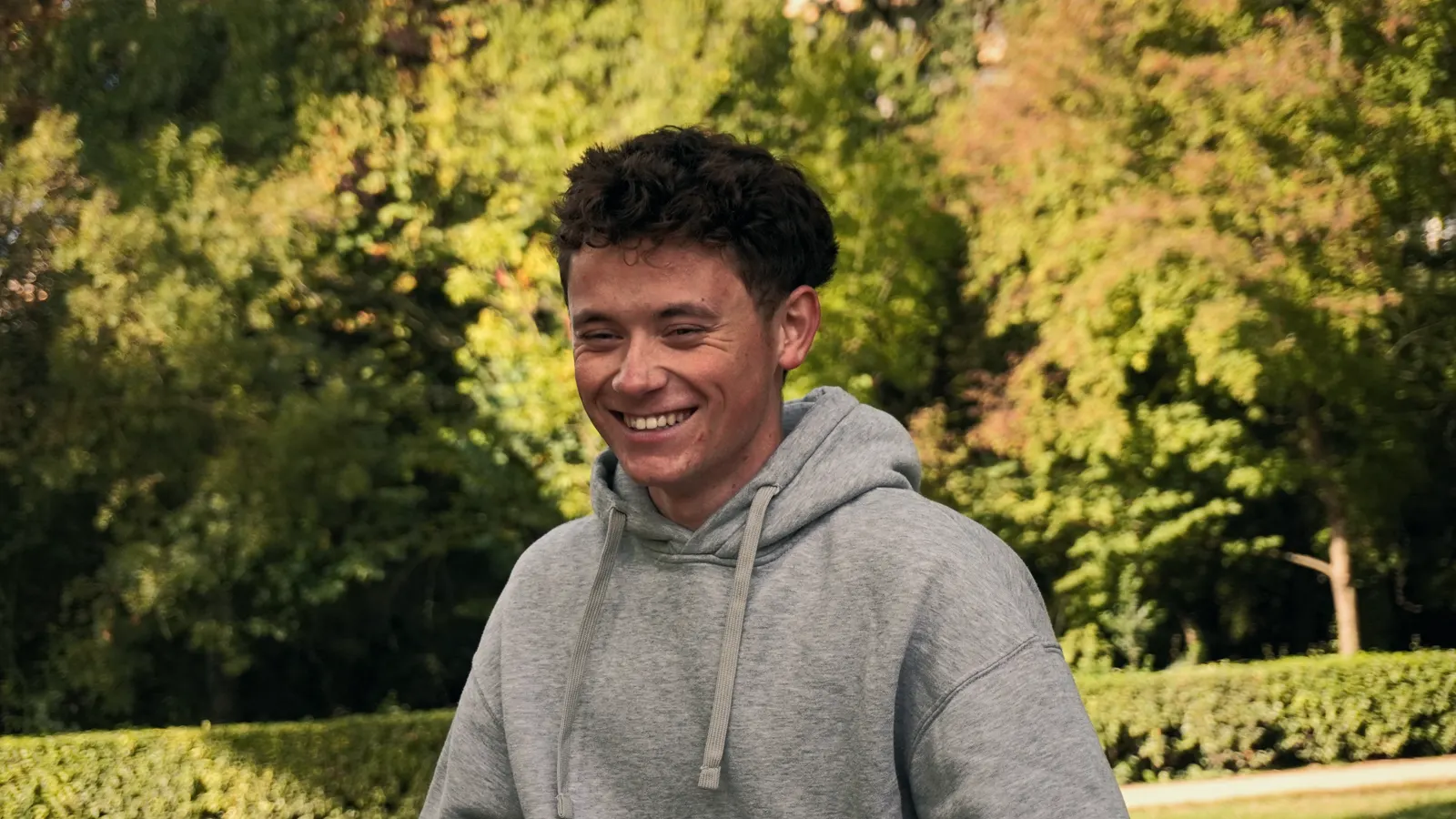 Un membre du club en sweat gris, souriant dans le parc